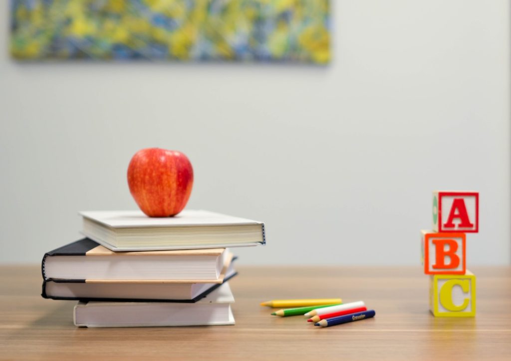 Apfel mit Schulbücher und Stiften auf Schreibtisch