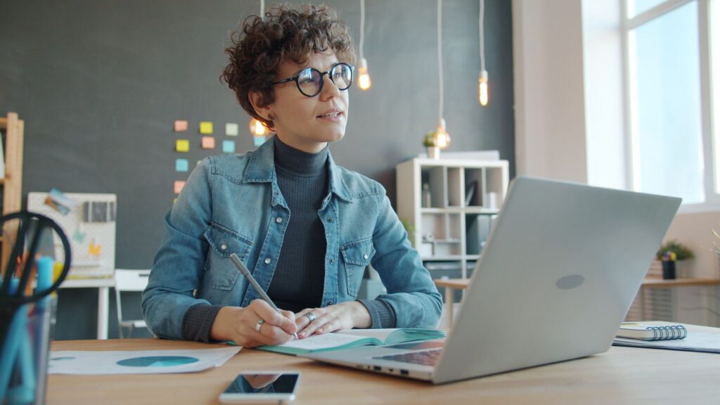 Junge Person plant ein Auslandspraktikum am Laptop mit Notizen und Checkliste