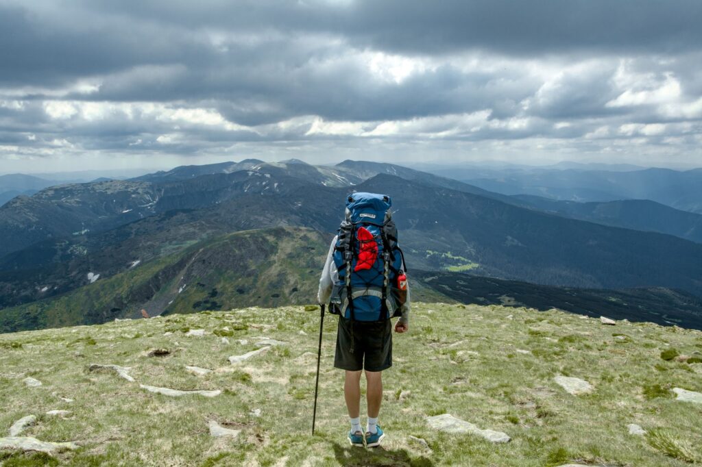 Junger Mann mit großem Reiserucksack steht bereit für seine Backpacking Tour im Ausland
