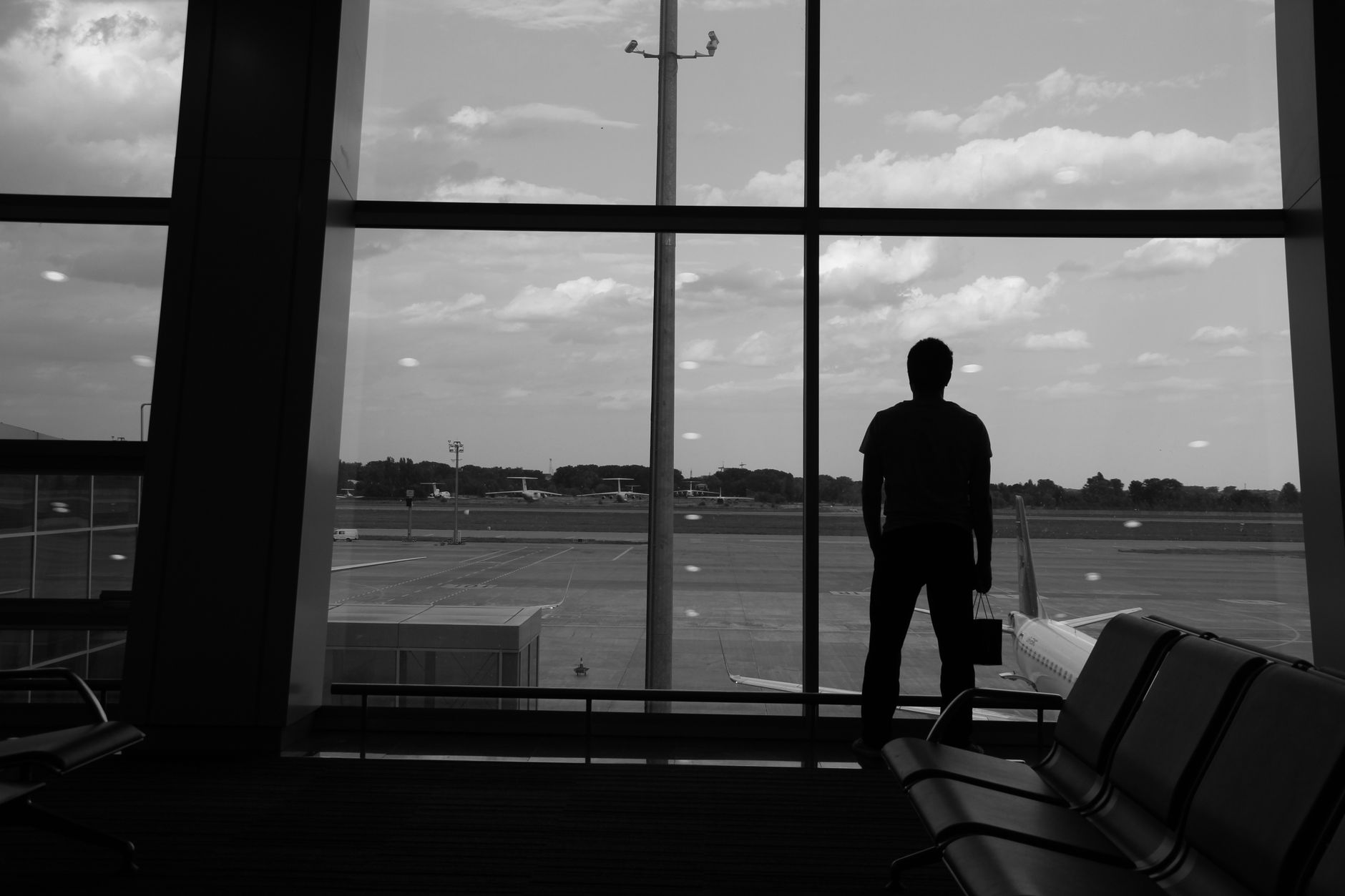 Alleinreisende Person blickt am Flughafen aus dem Fenster und plant ihr Work and Travel Abenteuer