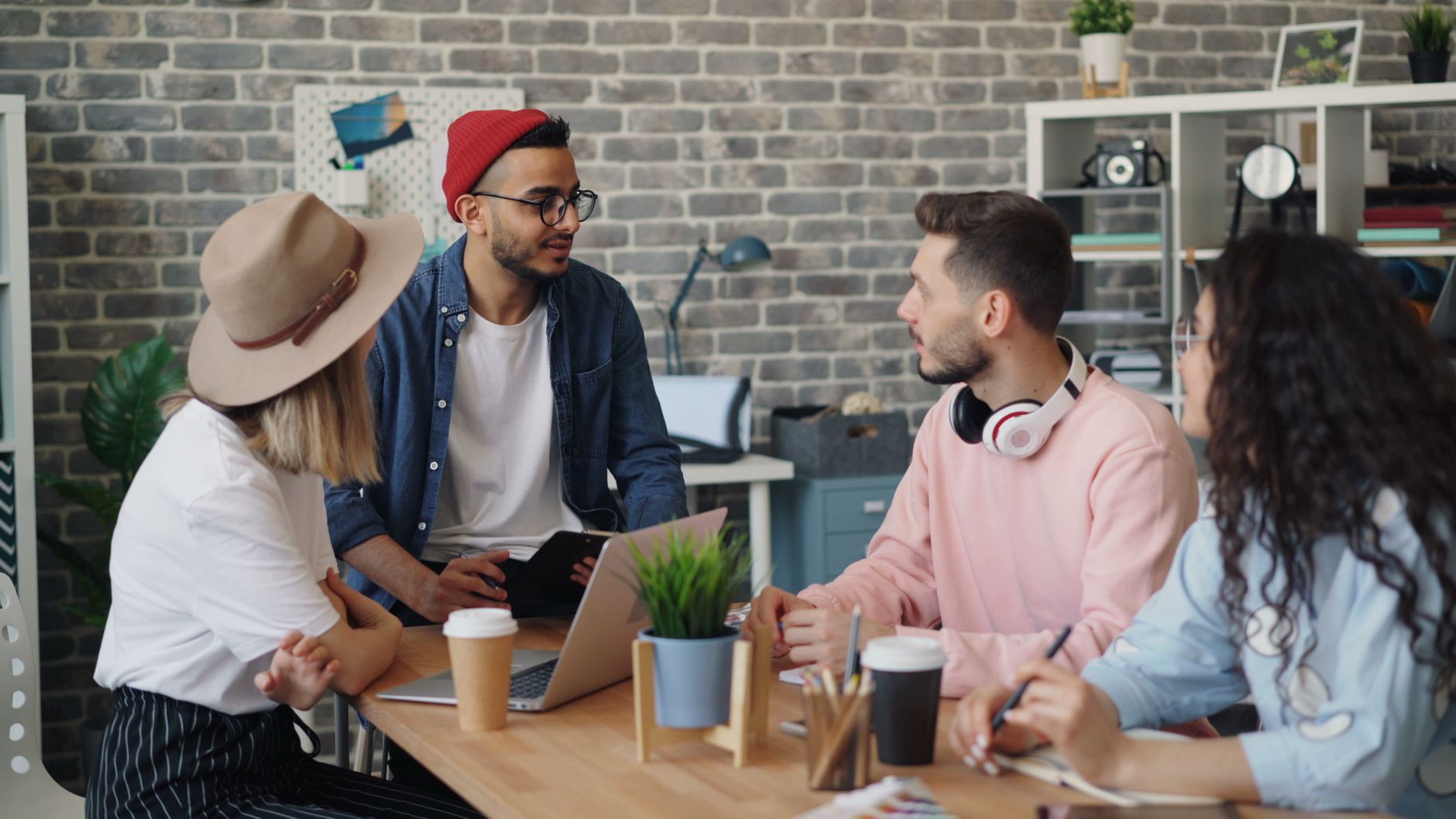 Junge Reisende teilt sich einen Coworking-Space mit internationalen Kollegen