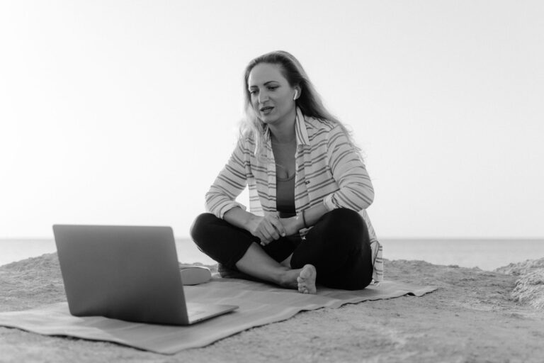 Remote Job erlaubt Workation: junge Person arbeitet mit Laptop am Strand